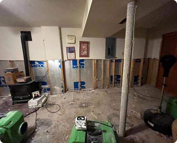 Technician in full protective suit and respirator removing mold-damaged material during a remediation job